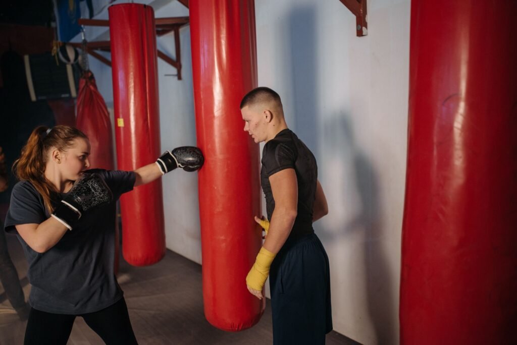 Boxing coach training an athlete with red punching bags for beginner boxing class article