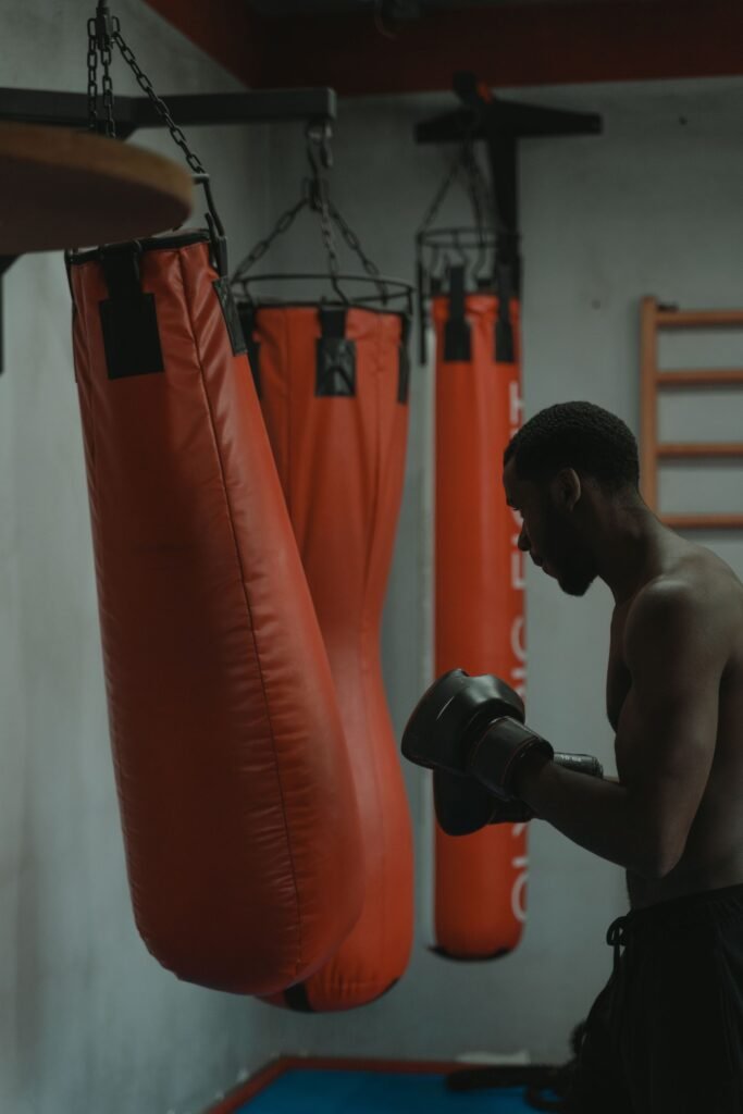 Boxer training hard on punching bags in a dark gym for strength and conditioning article